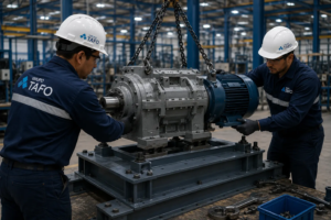 Montaje de maquinaria industrial con técnicos de Grupo TAFO posicionando y ensamblando equipo productivo suspendido con grúa dentro de una planta industrial.